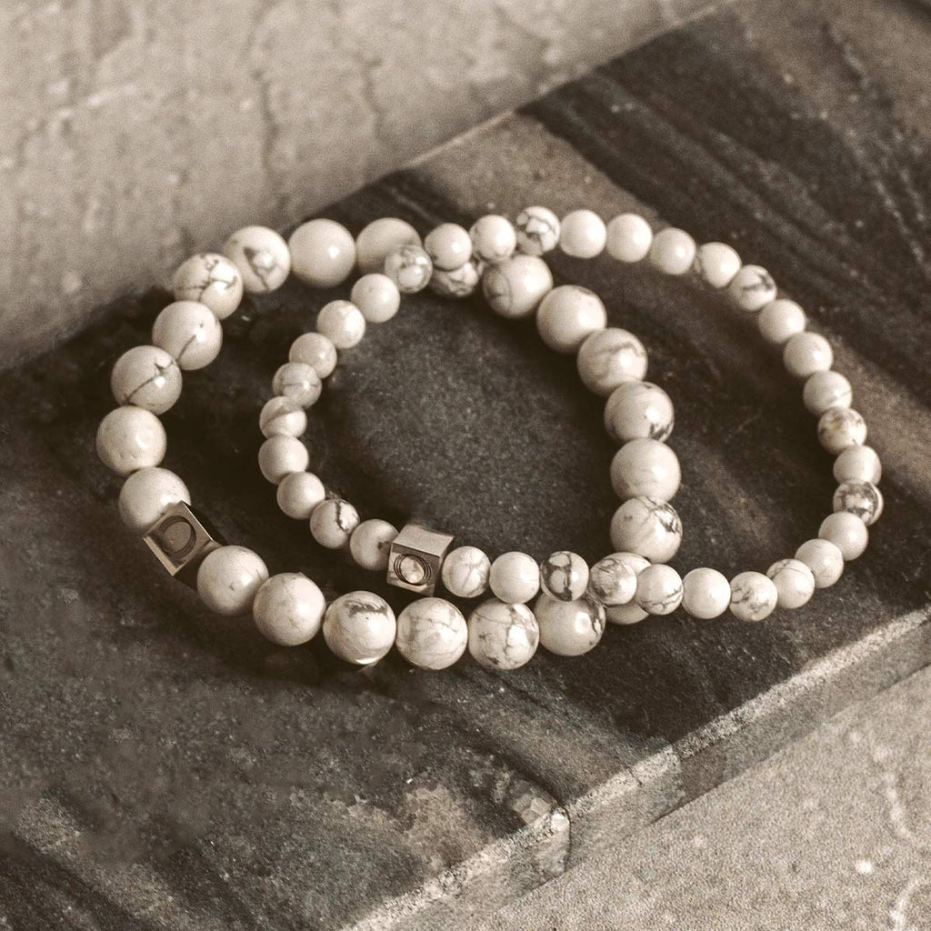 Deux bracelets en perles de pierre sur une dalle de pierre.