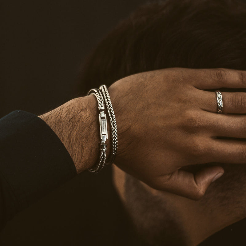 Een man die de 'Ninetwofive' Adam-armband voor heren van gevlochten sterlingzilver draagt, poseert met zijn hand achter zijn hoofd.