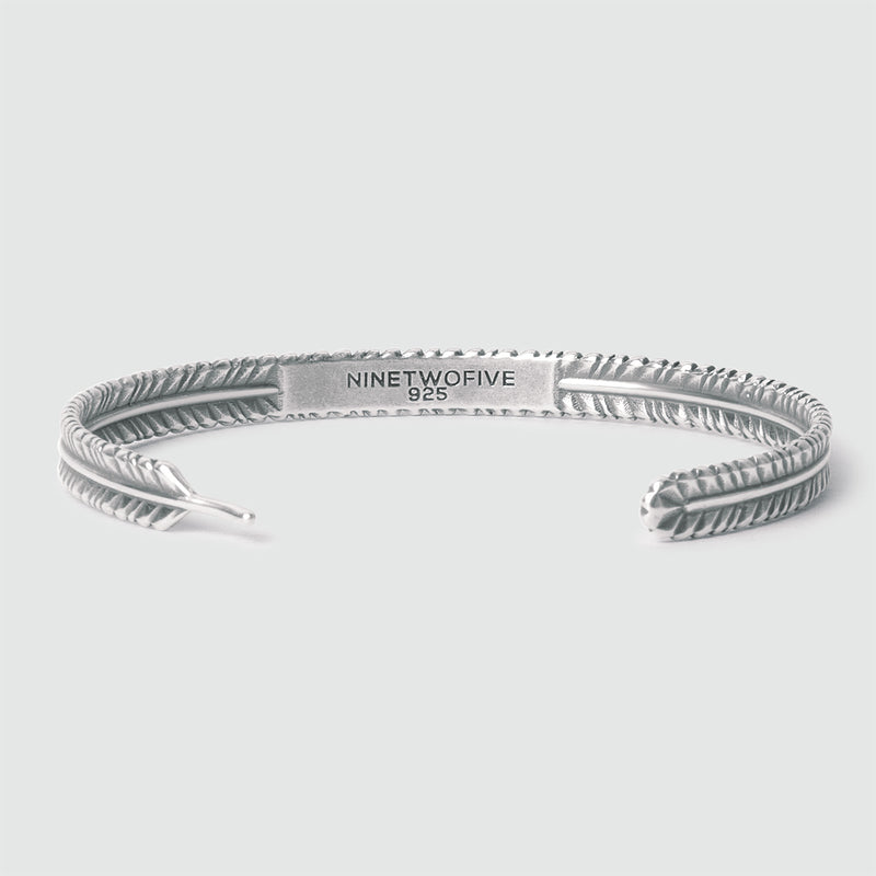Gros plan sur le bracelet pour homme « Zahir » en argent massif orné d'une plume, montrant l'emplacement idéal pour une gravure gratuite réalisée par Ninetwofive.