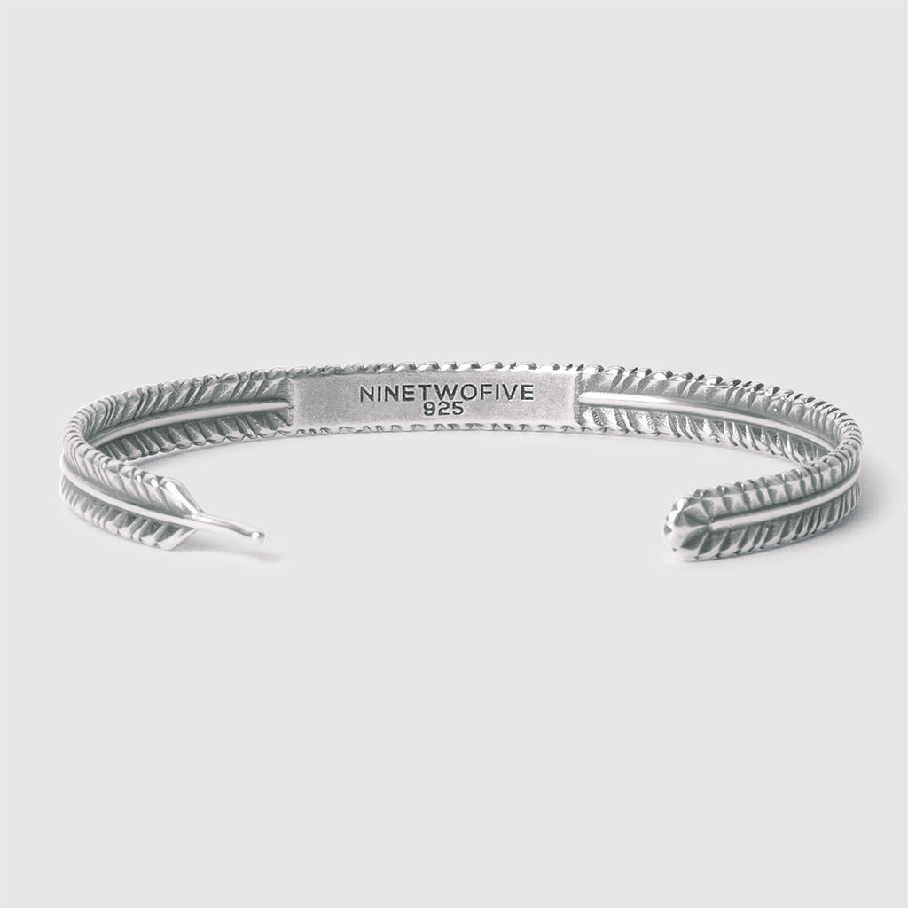 A personalised Zahir - Thin Sterling Silver Feather Bangle 6mm with an engraved design.