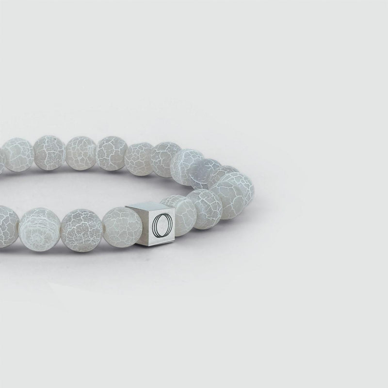 Gedetailleerd zijaanzicht van de witte kralenarmband voor heren Abyad, met duidelijk de gegraveerde Ninetwofive-logobedel.