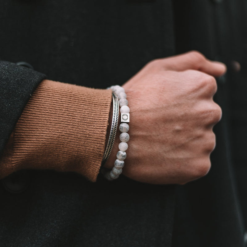 Man die de witte Abyad-armband voor heren draagt, met witte, verweerde stenen kralen en een zilveren manchet, van Ninetwofive.