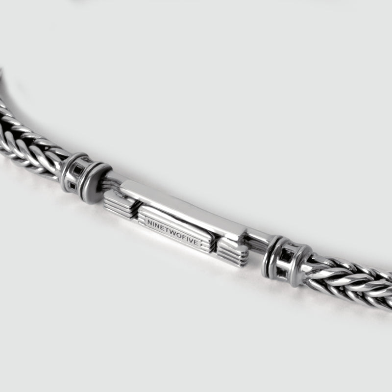 Afbeelding van de Adam zilveren gevlochten heren armband met gegraveerde sluitingen met het logo 'Ninetwofive'.