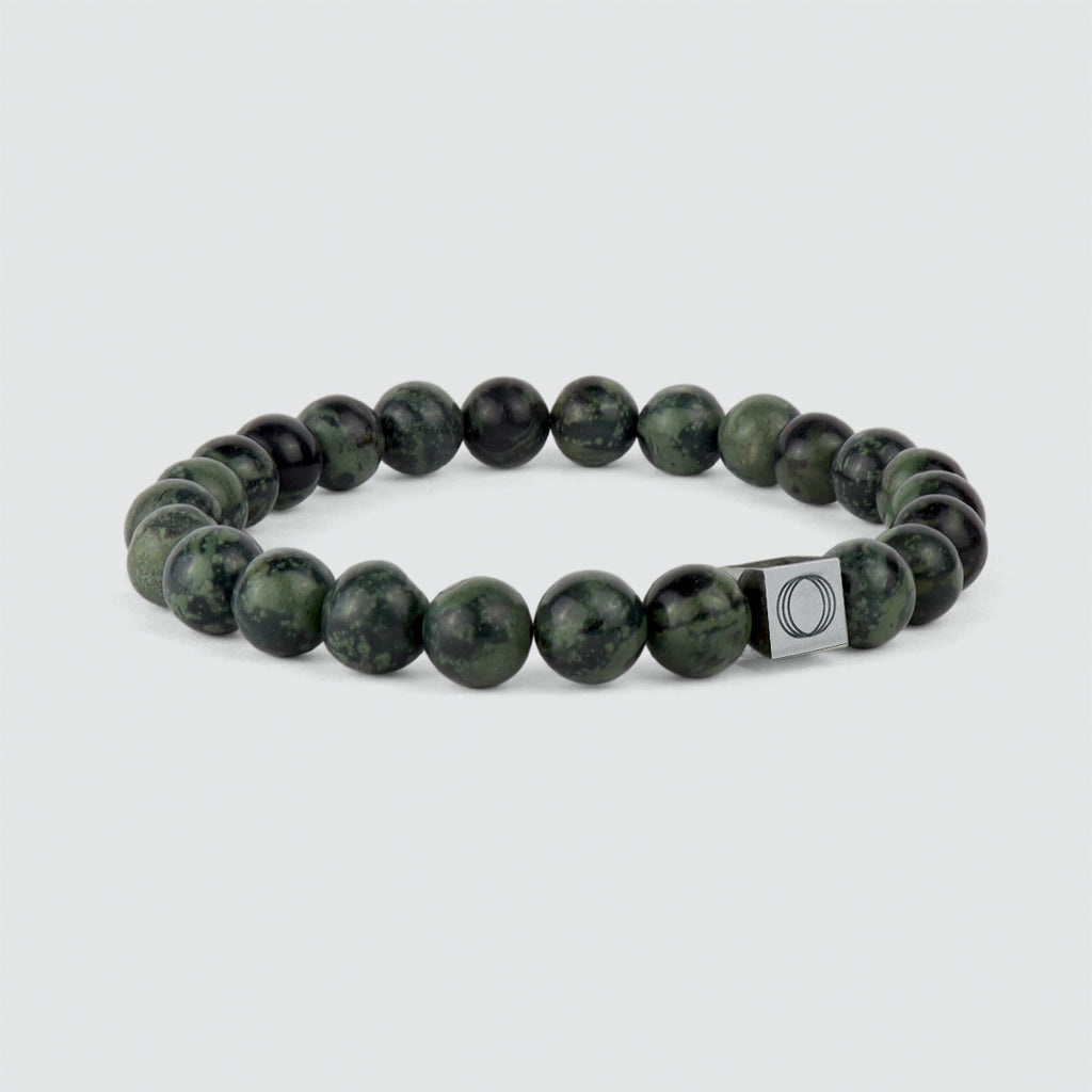 An Ahgdar - Green Beaded Bracelet 8mm, known for its weathering stone properties, and a sleek silver charm.
