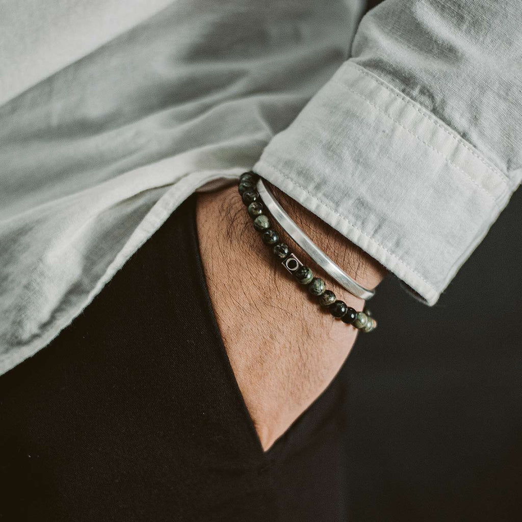 Description: A man wearing a black shirt and Ahgdar - Green Beaded Bracelet 6mm with weathering stone.
