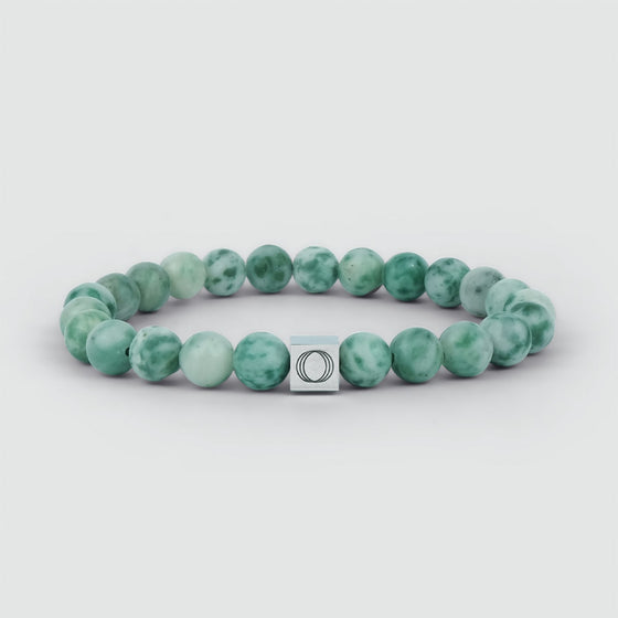 Gedetailleerd vooraanzicht van de Ahkdir-armband voor heren met jade-kralen, voorzien van een zilveren vierkant hangertje waarop het logo van de Ninetwofive is gegraveerd.