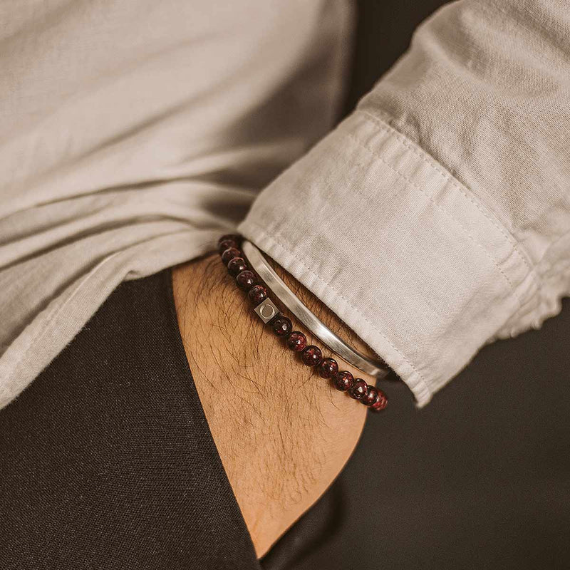 Model dat de Ahmar-rode heren armband met kralen van Ninetwofive showt, gemaakt van gladde jade-steentjes.