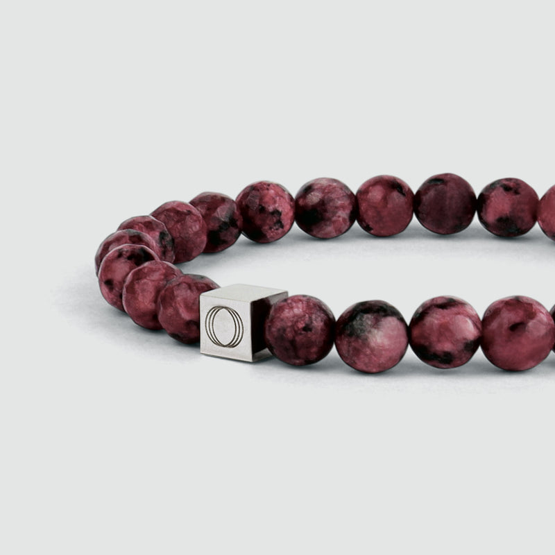 Close-up side angle of the Ahmar mens red beaded bracelet, showing the beads and the visible Ninetwofive logo detail.