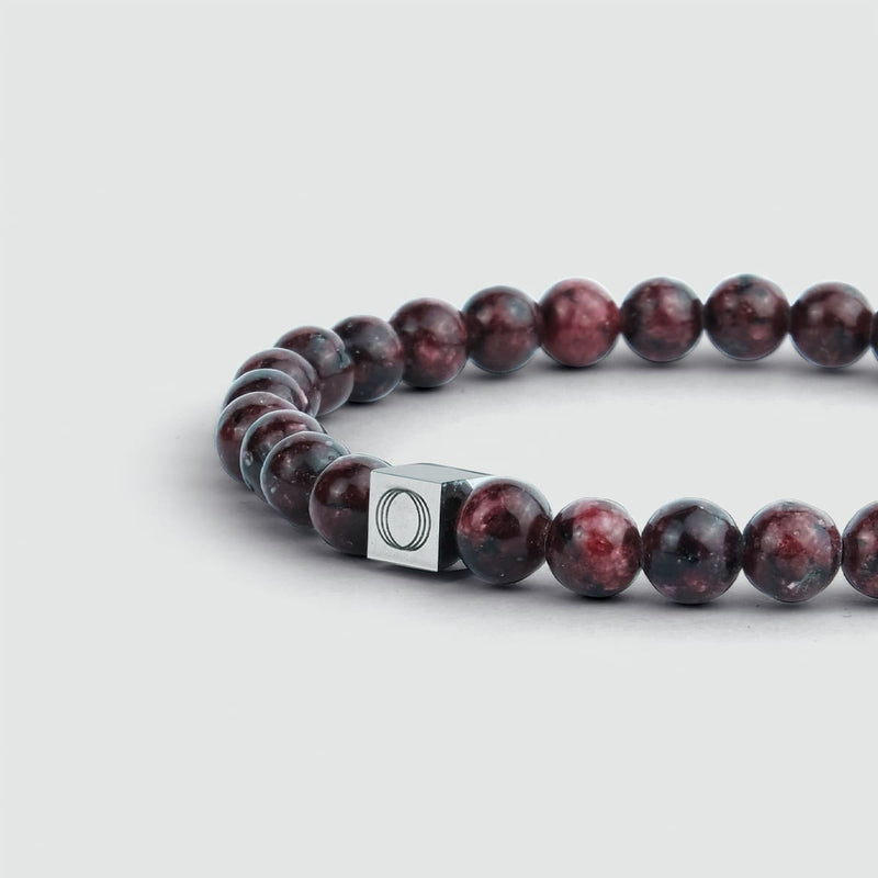 Zijaanzicht van de Ahmar-heren armband met rode jade-kralen en het gegraveerde ‘Ninetwofive’-logo.