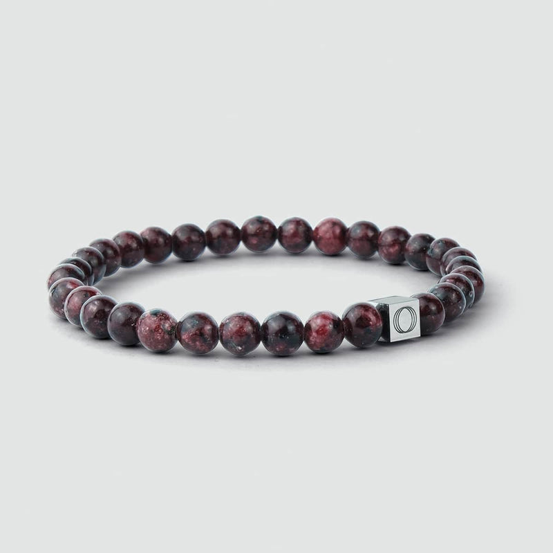 Close-up van de Ahmar-heren armband met rode jade-kralen, waarop het logo van Ninetwofive is gegraveerd.