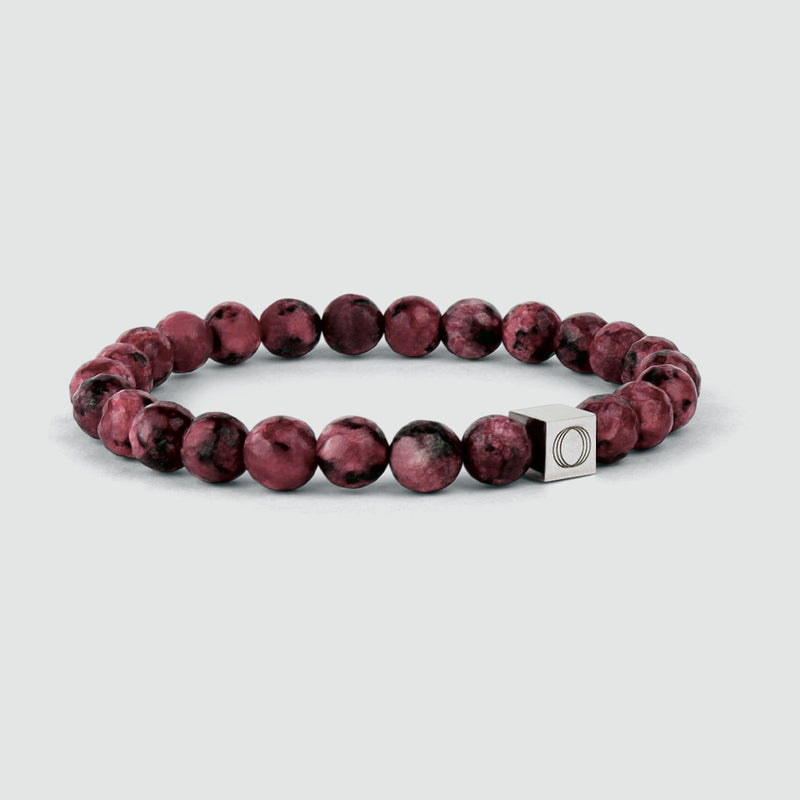 Side angle of the Ahmar mens red beaded bracelet, showing the beads and the visible Ninetwofive logo detail.