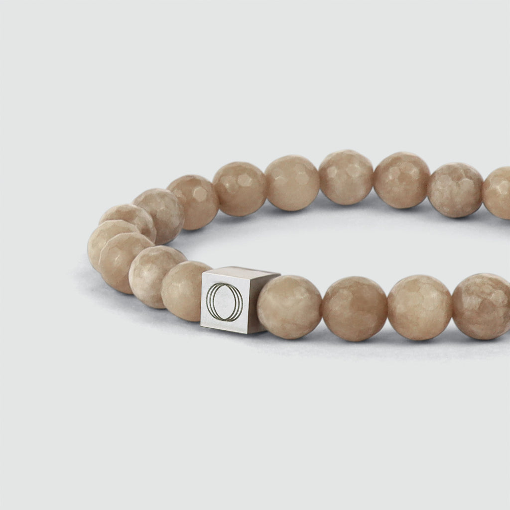 Un bracelet en perles beige de 8 mm avec un fermoir en argent.