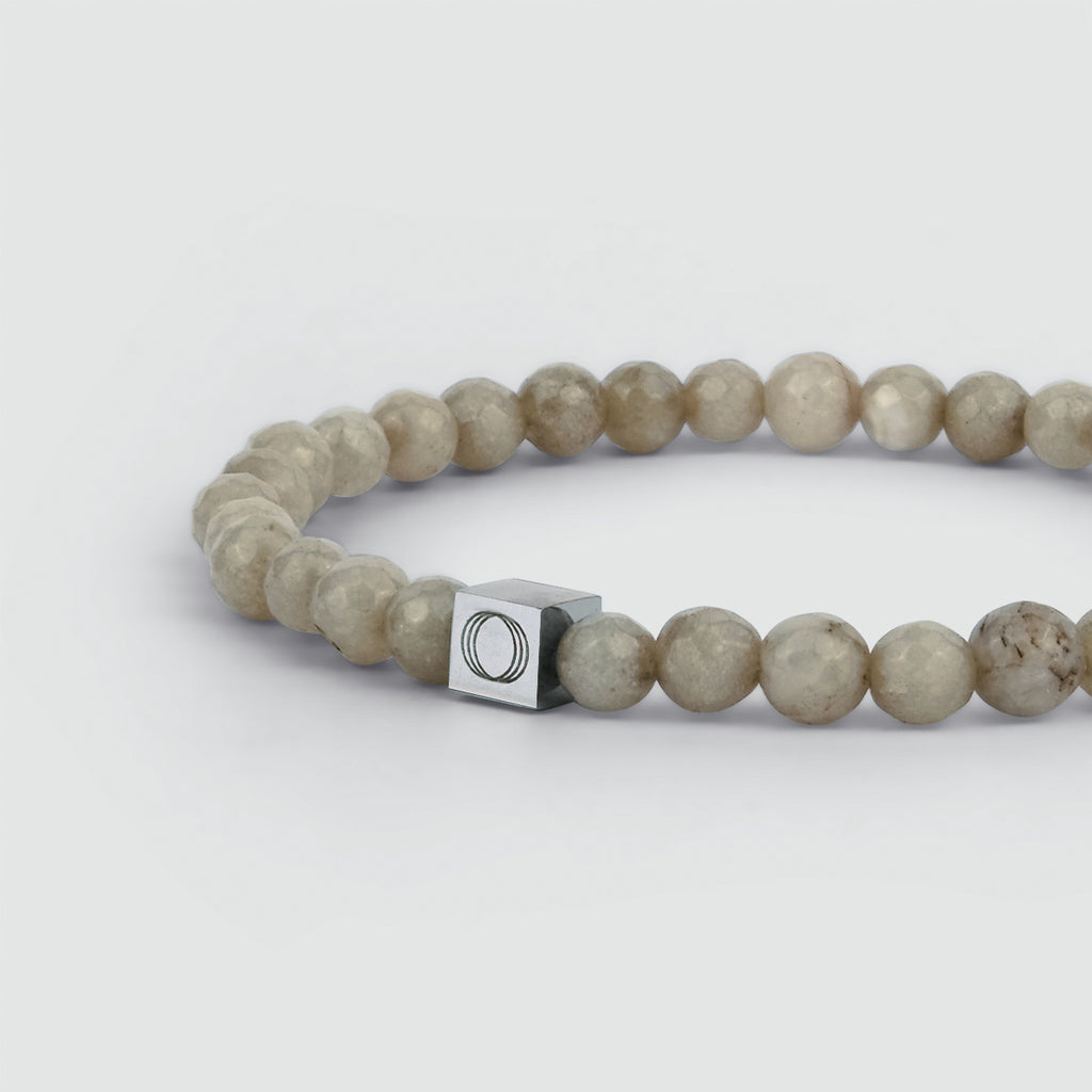 Un bracelet en perles beige de 6 mm, sculpté en jade, avec un fermoir en argent.
