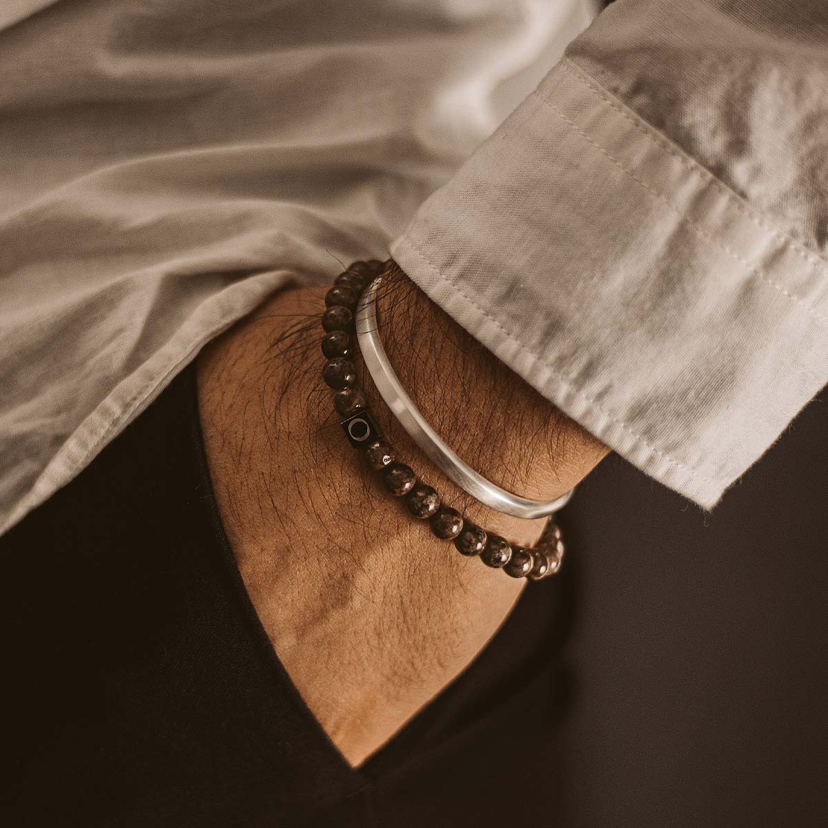 A man's wrist with an Albuna - Brown Beaded Bracelet 6mm on it.