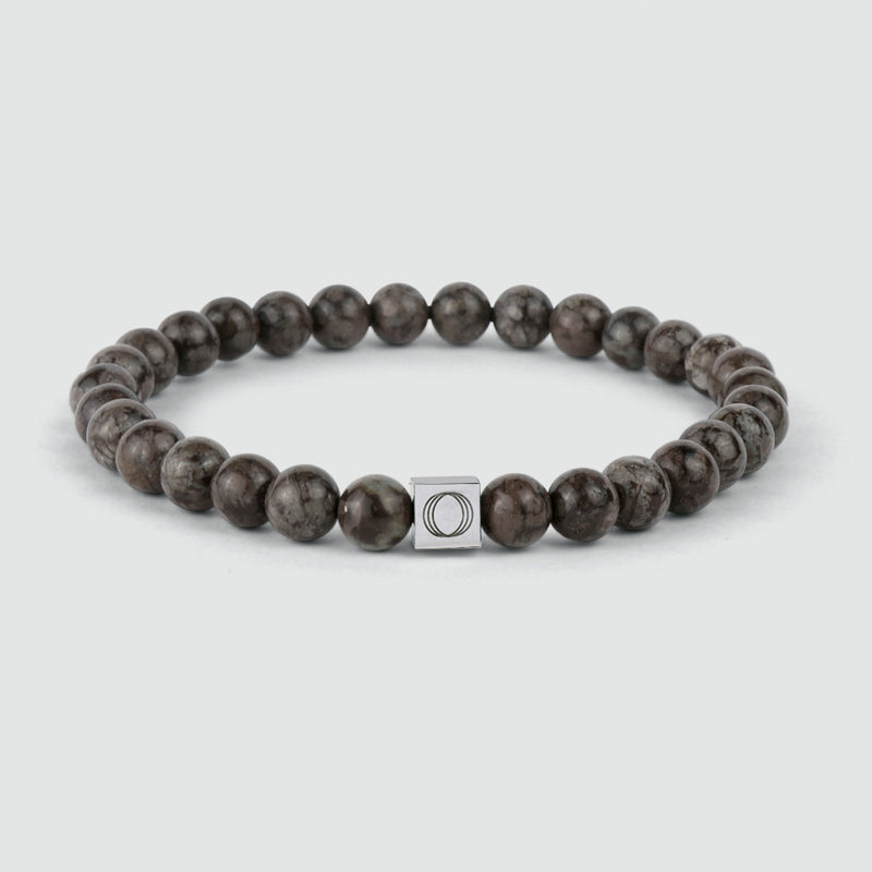 Een bruine kralenarmband van Albuna met een steenkraal in de vorm van een sneeuwvlok en het gegraveerde logo ‘Ninetwofive’.