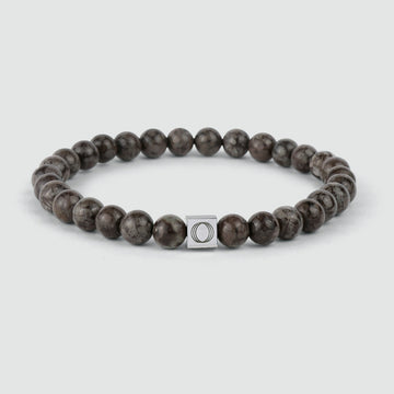 Un bracelet en perles Albuna - Brown 6mm avec une perle en pierre flocon de neige et une perle en argent.