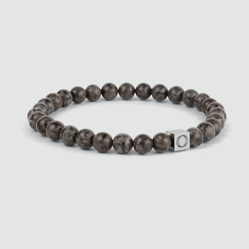 Zijaanzicht van de bruine kralenarmband voor heren van Albuna, met de sneeuwvloksteen en het Ninetwofive-logodetail.