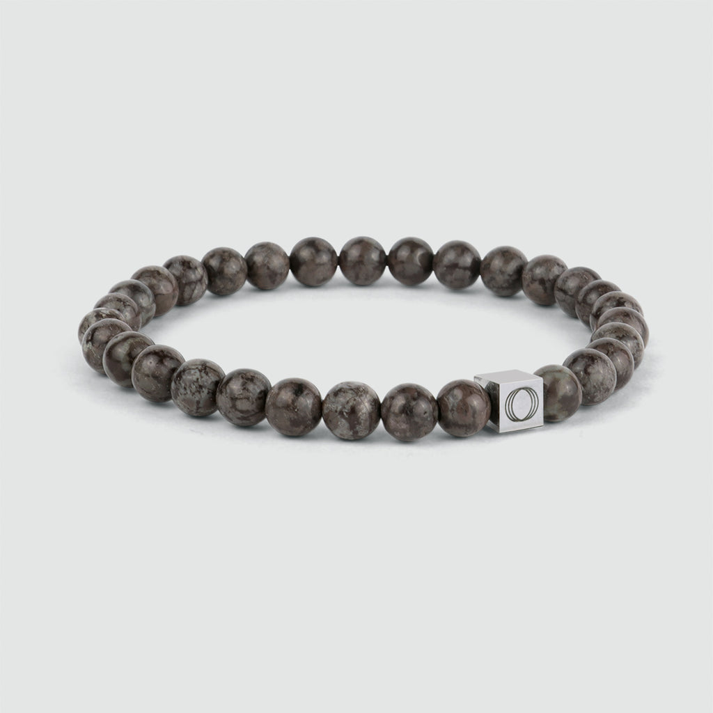 Un bracelet en perles Albuna - Brown 6mm avec une perle en pierre flocon de neige et une breloque en argent.