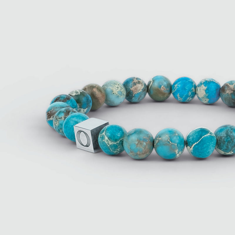 Close-up vanuit een zijdelingse hoek van de Alfiruz turquoise heren armband met kralen, waarop de kralen en het zichtbare Ninetwofive-logo te zien zijn.