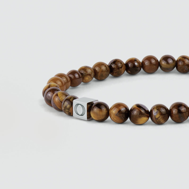 Close-up van de Alnamr-armband voor heren met tijgeroogkralen, waarop de kralen en het logo van Ninetwofive goed te zien zijn.