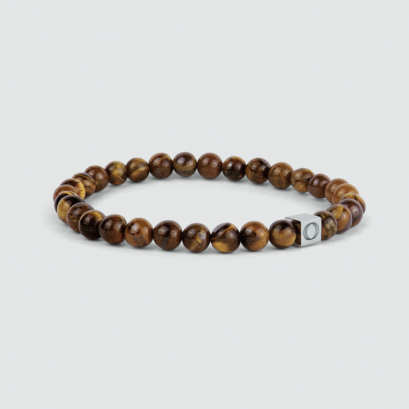 Zijaanzicht van de Alnamr-armband voor heren met tijgeroogkralen, waarop de kralen en het gegraveerde Ninetwofive-logo te zien zijn.