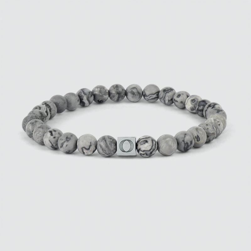 Ein graues Perlenarmband von Alrazas mit einer Marmorperle und eingraviertem „Ninetwofive“-Logo.