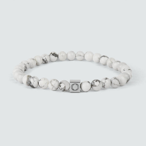An Alrukham white beaded bracelet with detailed look of beads and engraved Ninetwofive logo.