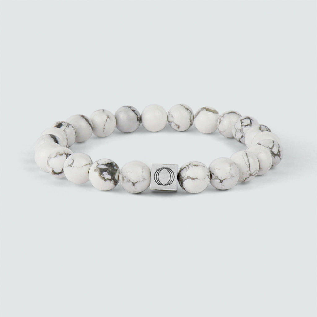A Alrukham - Bracelet en perles blanches de 8 mm portant la lettre o et orné d'une pierre d'altération.
