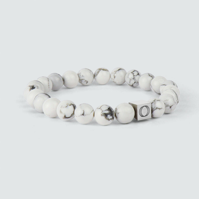 Een schuin perspectief op de Alrukham-armband voor heren met kralen, waarop de gedetailleerde afwerking van het witte marmer en het logo van Ninetwofive goed te zien zijn.