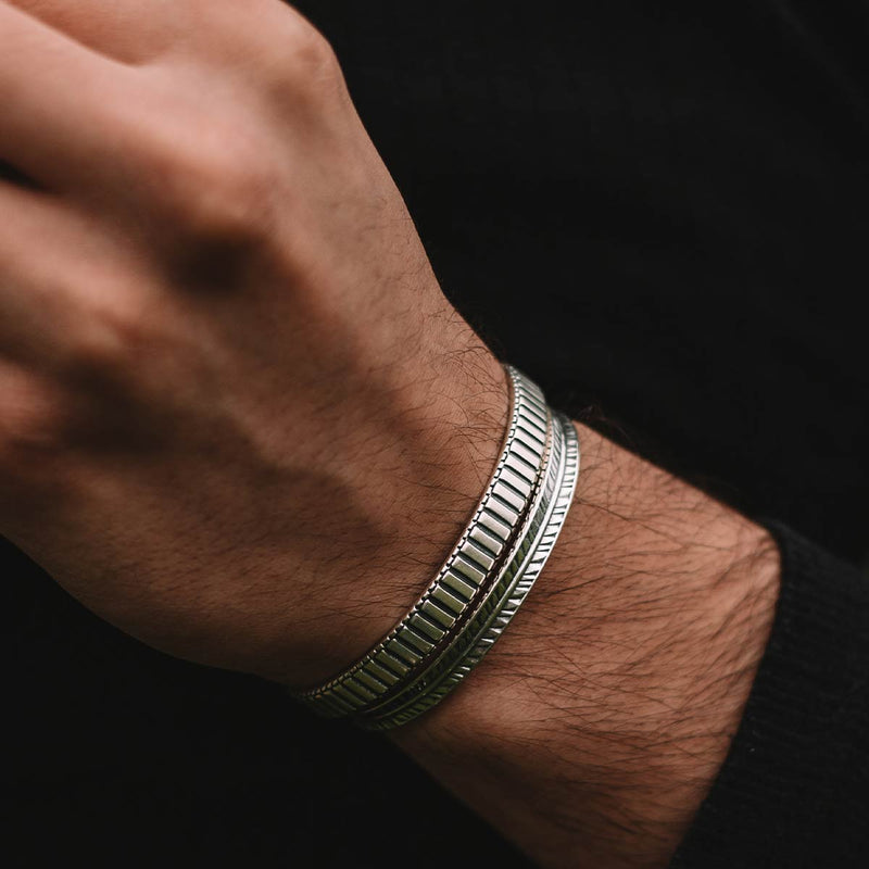 Eine Nahaufnahme der Hand eines Mannes, die einen Kenan-Armreif aus Sterlingsilber für Herren, 7 mm, trägt.