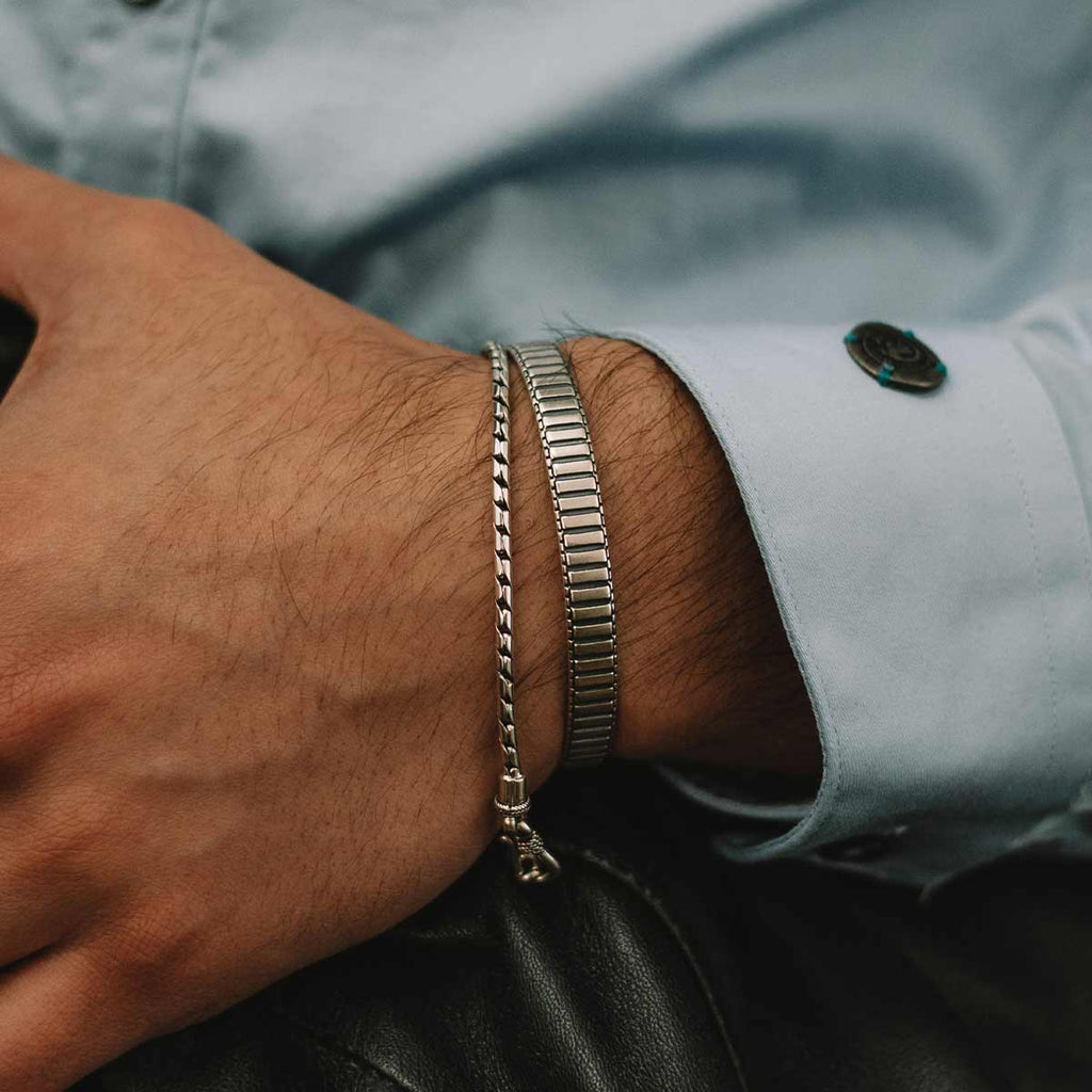 Een man met een Kenan - Sterling Zilveren Bangle Armband 7mm om zijn pols.
