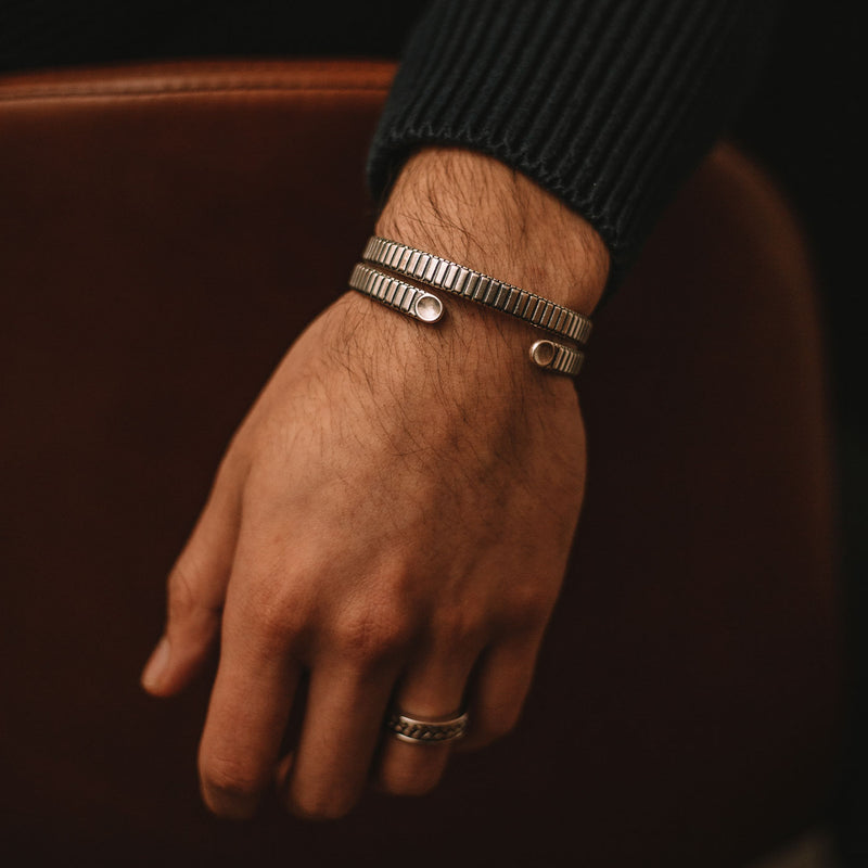 Ein Mann in einem schwarzen Pullover, der eine 7-mm-Kette von Kenan aus Sterlingsilber für Herren Armreif sowie einen Silberring am Ringfinger trägt.