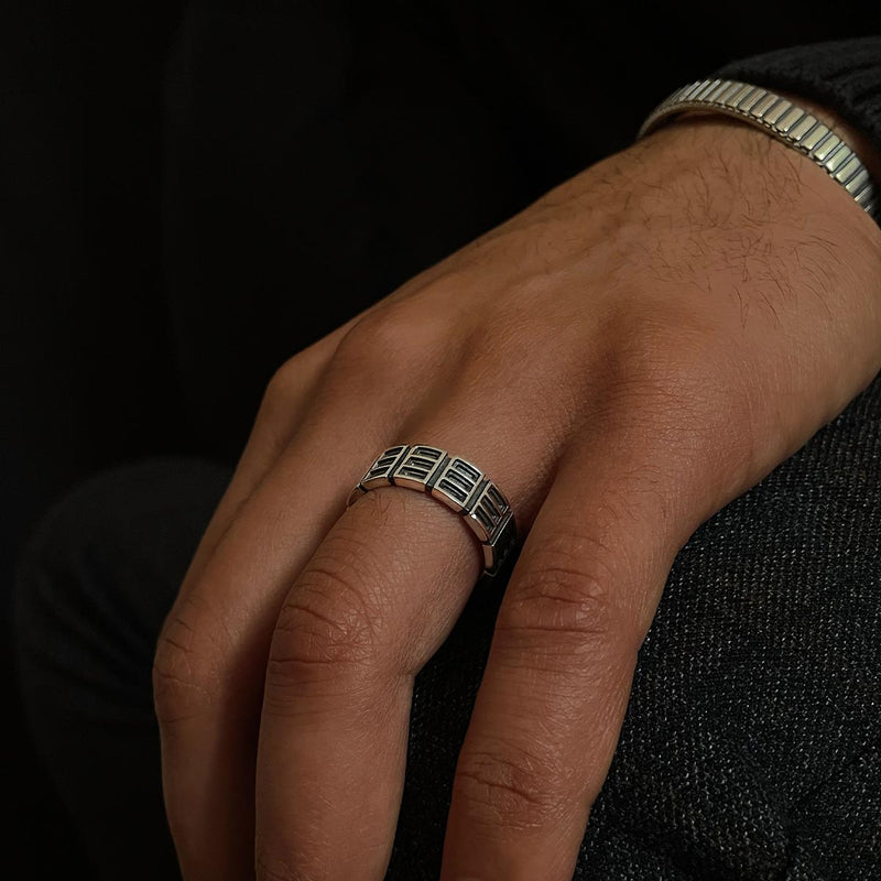 Ein Model präsentiert einen gravierten Ayman oxidierten Sterling Silber Herrenring und ein Ninetwofive Manschettenarmband.