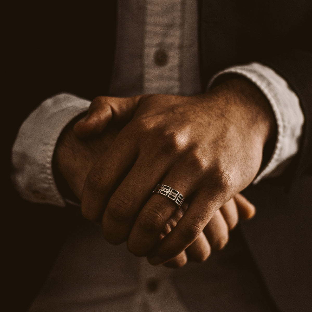 A man in a suit holding an engraved Ayman - Oxidized Sterling Silver Ring 7mm.