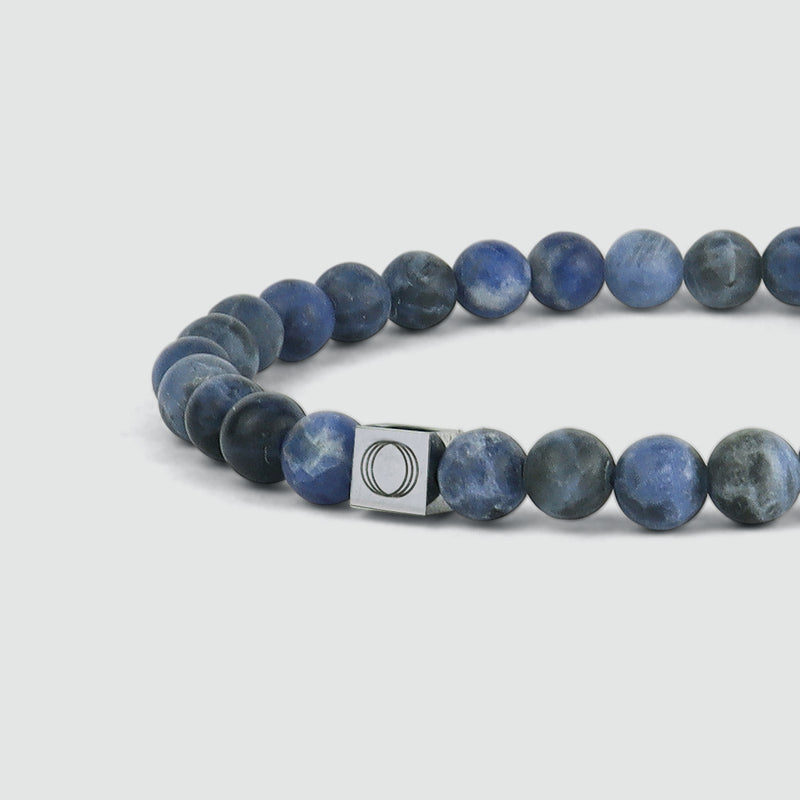 Zijaanzicht van de blauwe kralenarmband voor heren van Azraq, waarbij het gegraveerde logo van de ‘Ninetwofive’ goed tot zijn recht komt.