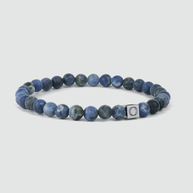 Zijaanzicht van de blauwe heren armband met Azraq-sodalietkralen, waarop het logo van Ninetwofive is gegraveerd.