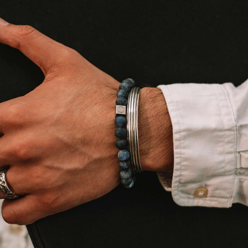 Man in a white shirt showcasing the blue sodalite Azraq bracelet layered with a sterling silver bangle.