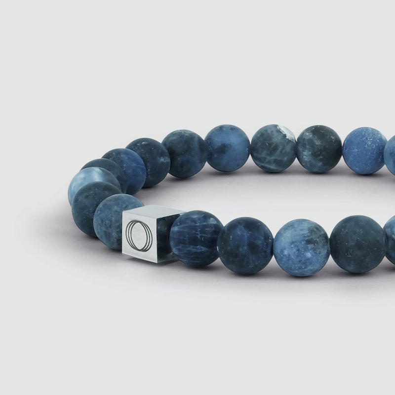 Close-up side view of the Azraq sodalite men's blue beaded bracelet, highlighting the Ninetwofive logo engraving detail.