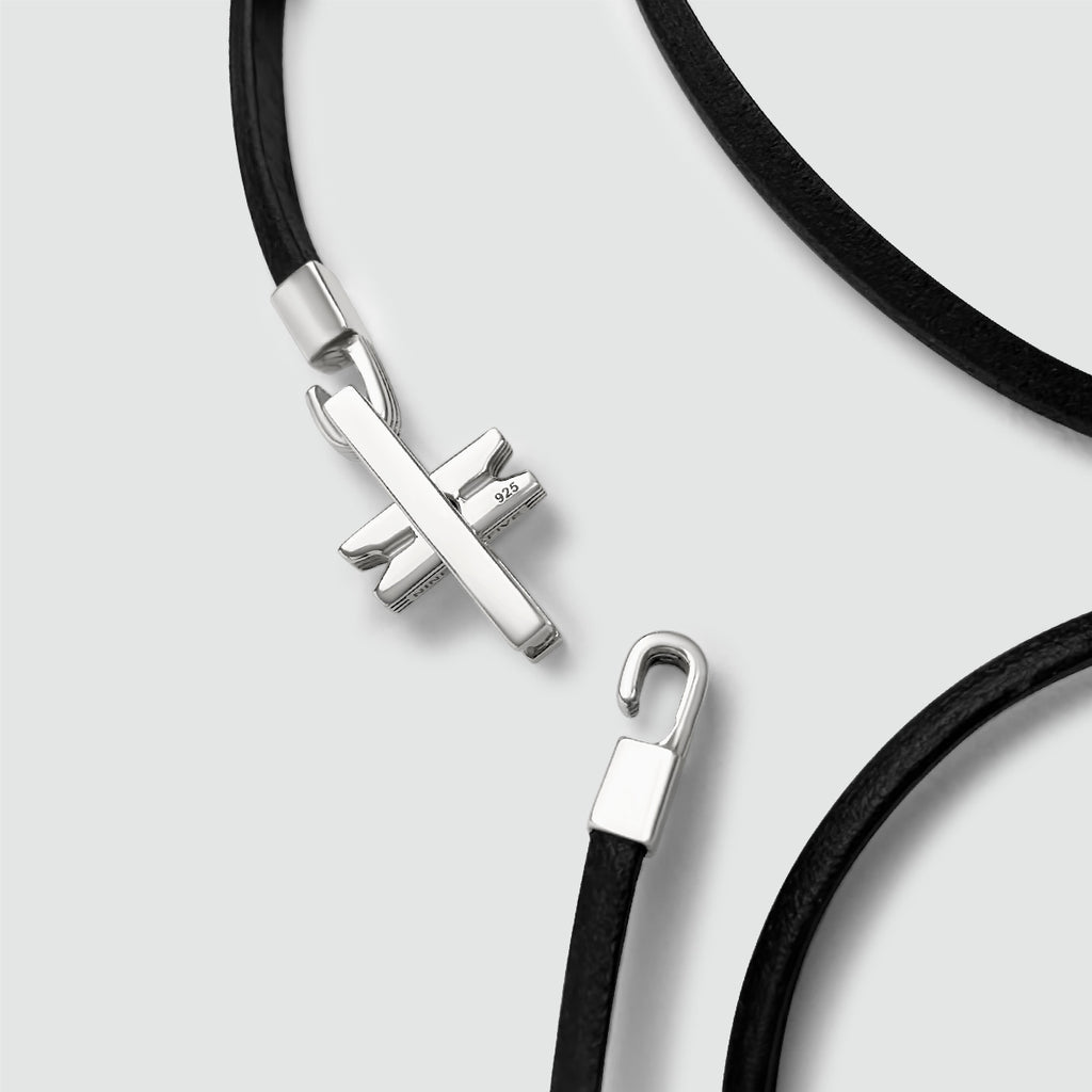 A black leather bracelet with a silver cross pendant.