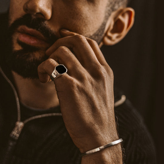 A man with a beard wearing a Naim black onyx mens signet ring and silver cuff by Ninetwofive.