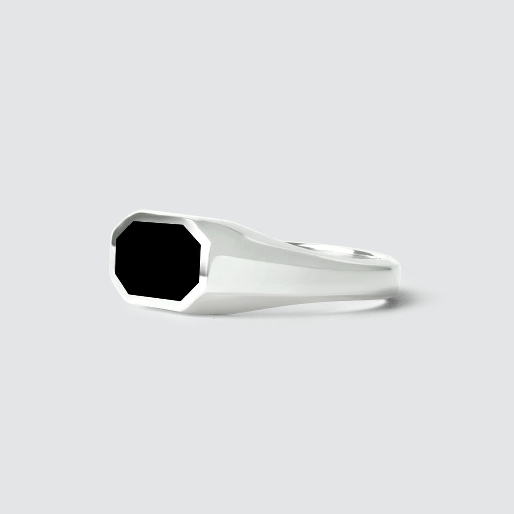 Een Aniq - Elegante Zwarte Onyx Zegel Ring 7mm zegel ring met een gegraveerd ontwerp, set tegen een maagdelijk witte achtergrond.