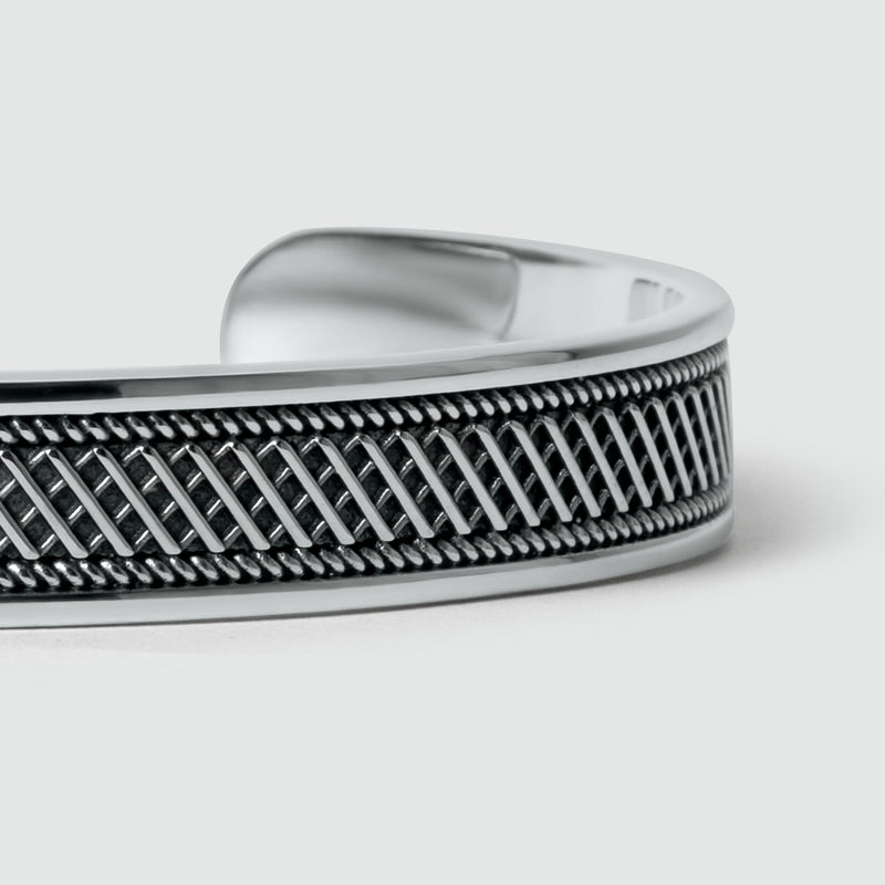 Een close-up van de gepersonaliseerde Kaliq-armband voor heren van geoxideerd sterlingzilver met een gedetailleerd ontwerp.