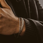 Un homme en manteau noir portant le bracelet Idris - Braided Silver Jonc 8mm.
