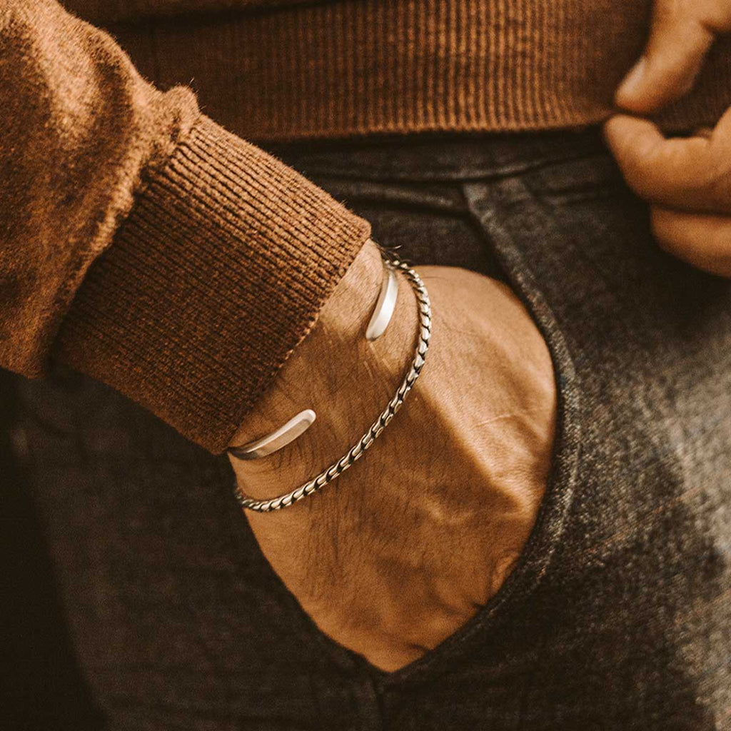 Un homme portant une paire de bracelets en argent NineTwoFive , dont un bracelet minimaliste en argent sterling de 2,5 mm, personnalisé et gravé Emir.