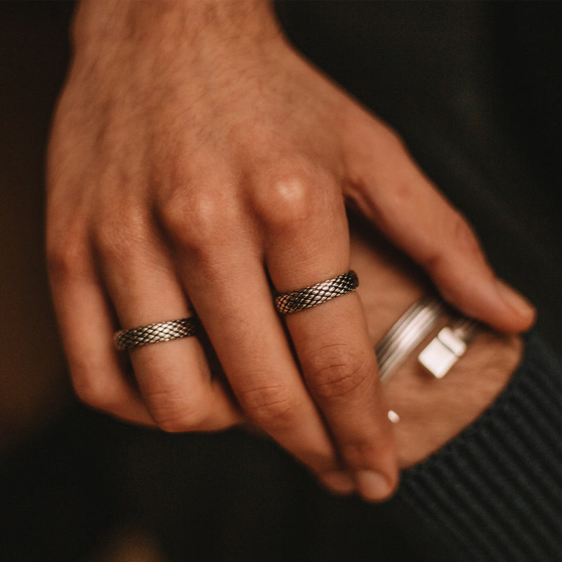 Man in black cozy sweater wears the Ferran oxidised sterling silver ring and a mens ring and cuff by Ninetwofive.