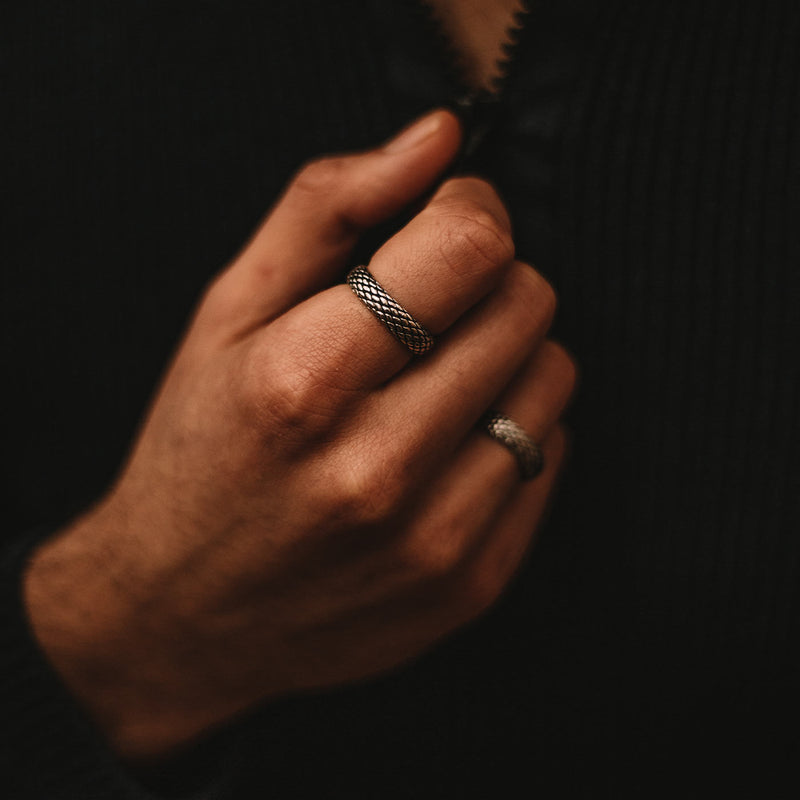Man in black long sleeve shirt wears two Ferran oxidised sterling silver mens rings styled by Ninetwofive