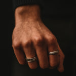 Ein gravierter Ferran - Oxidierter Sterling Silber Ring 6mm schmückt die Hand eines Mannes.