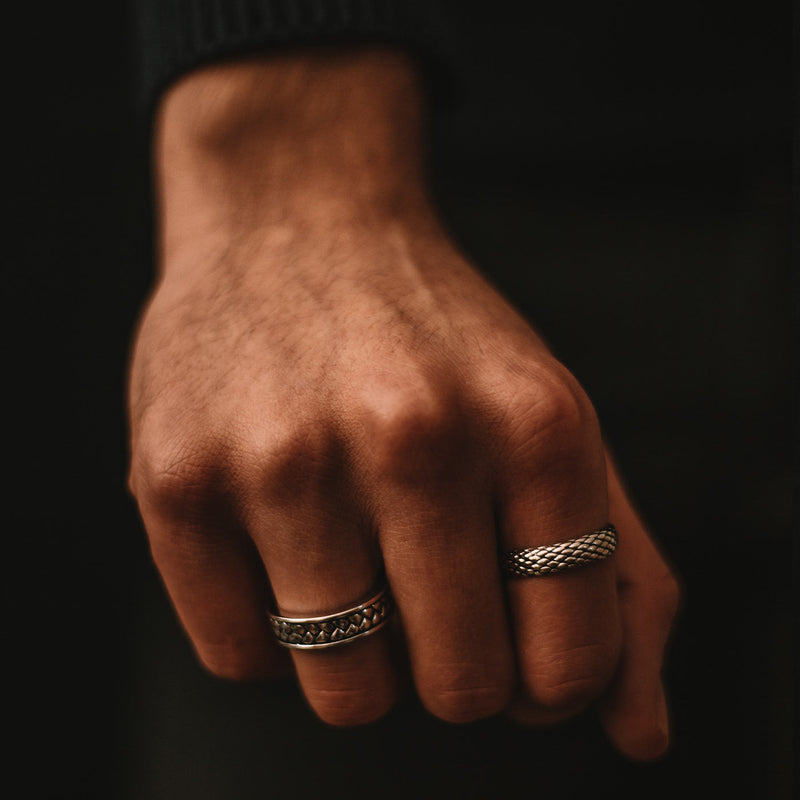 Man's hand wears the Ferran oxidised sterling silver ring and a mens ring, styled by Ninetwofive.
