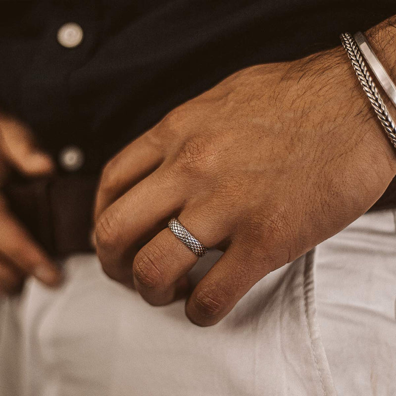 Model's hand wears the Ferran oxidised mens silver ring on his ring finger, layered with a silver bracelet and cuff from Ninetwofive.