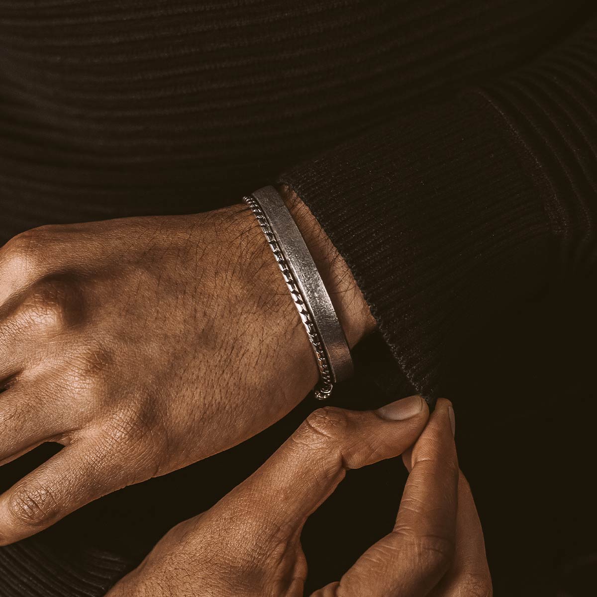 Die Hand eines Mannes stellt einen Fudail - Rough Brushed Sterling Silver Bangle 8mm ein.